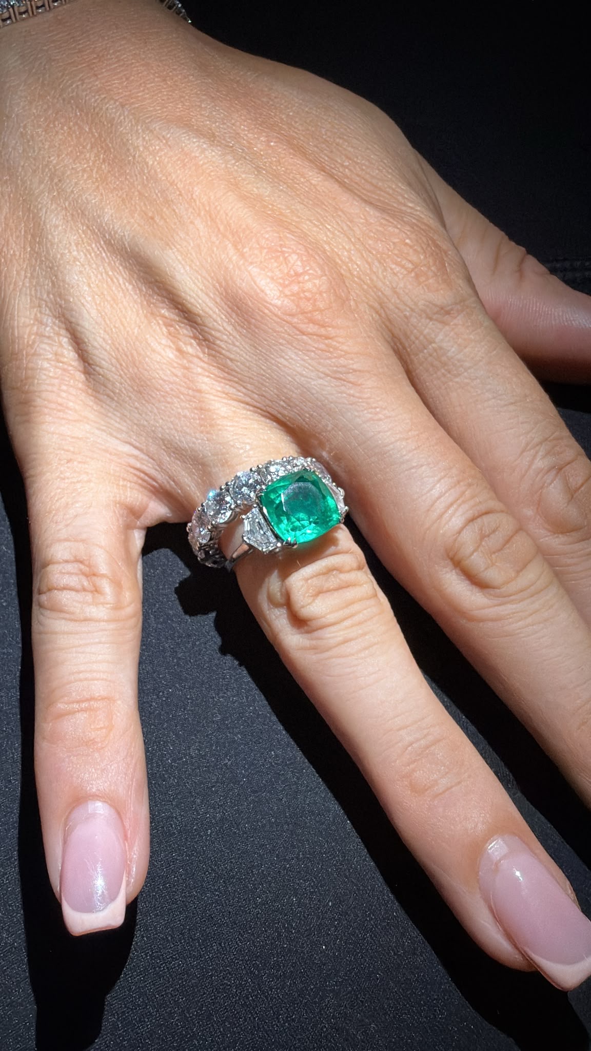 Bespoke emerald and diamond ring worn on hand